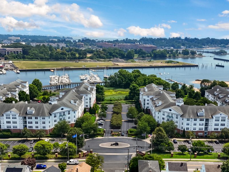 Aerial view of TGM Anchor Point waterfront apartments with marina and scenic coastal landscape.