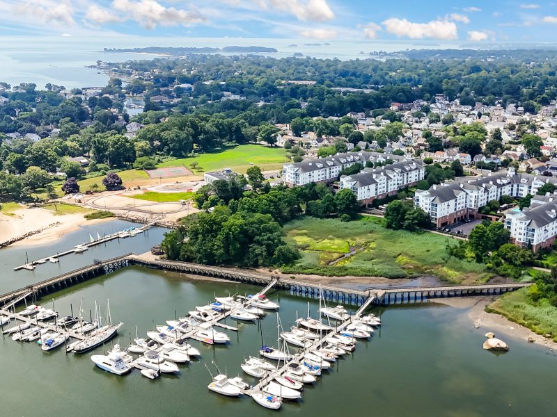 Aerial view of TGM Anchor Point marina with yachts, beach, waterfront homes, and greenery.