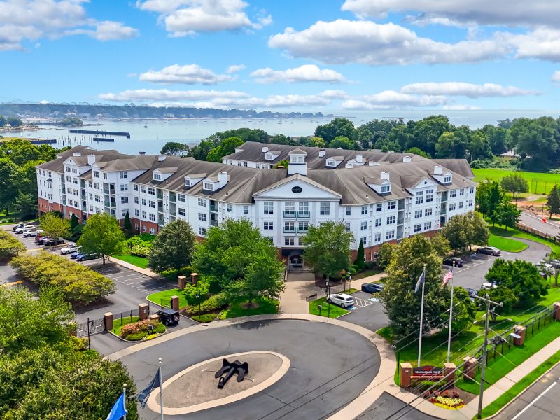 Aerial view of TGM Anchor Point resort with modern architecture, lush landscaping, and waterfront scenery.